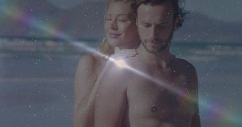 Romantic couple embracing at tranquil beach with light reflections