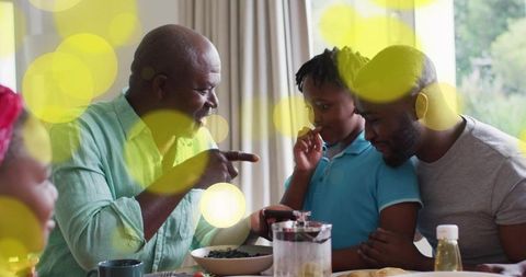 Grandfather pointing while father comforting son at cozy breakfast table with berries