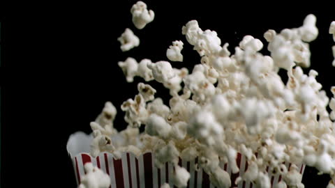 Popcorn Spilling from Striped Container on Black Background
