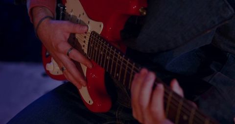 Close-Up of Hands Playing Red Electric Guitar in Studio Setting
