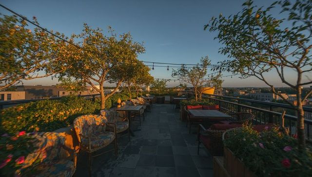 Rooftop garden terrace basking in golden hour light with cozy wicker seating and patterned chairs