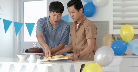 Two Men Preparing for Indoor Birthday Celebration with Decoration