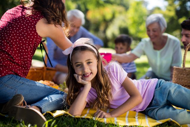 Girl Relaxing on Blanket with Family Having Picnic in Park - Download Free Stock Photos Pikwizard.com