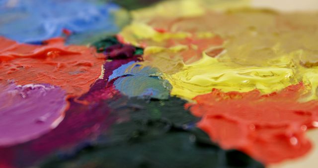 Vibrant oil paints blend on a palette, showcasing a spectrum of colors with a focus on the yellow and red hues. This image captures the essence of an artist's tool, ready for the creative process.