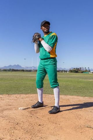 African American Baseball Pitcher Standing on Mound Preparing to Pitch in Green Uniform