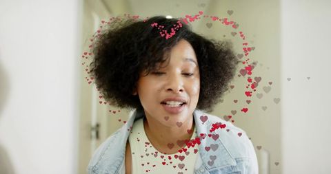 Mid-adult woman smiling with heart overlays wearing denim jacket in bright home hallway