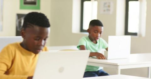 African American teens using laptops in bright classroom learning technology and focus