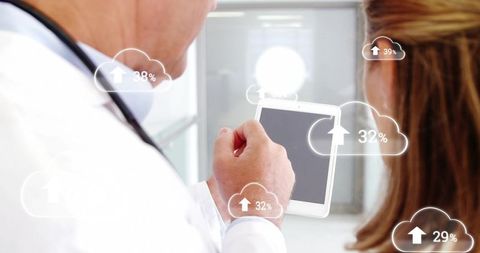 Doctor showing tablet with cloud data analytics to senior patient in clinic hallway