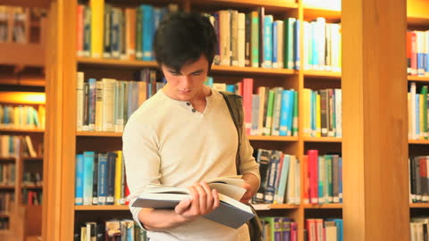 Young Man Focusing on Book in Vibrant Library Environment