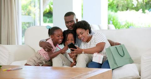 Happy African American Family Sharing Fun Moment at Home with Smartphone