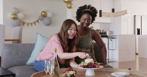 Joyful Lesbian Couple Lighting Cake Candles at Home Celebration