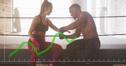 Trainer adjusting hand wraps on female boxer on ring apron with green performance graph