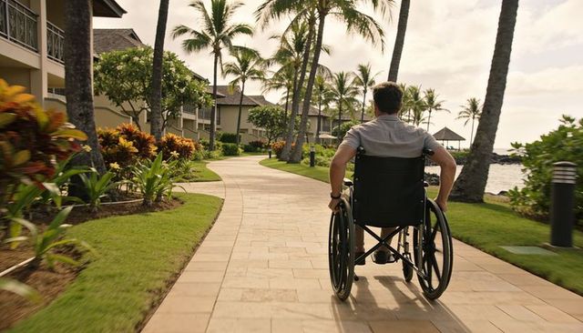 Rolling along palm-lined oceanfront walkway at tropical resort in manual wheelchair