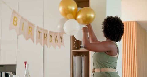 Woman removing birthday decorations in kitchen