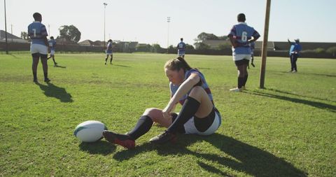 Focused Teenage Girl Sitting on Rugby Field Prior to Game