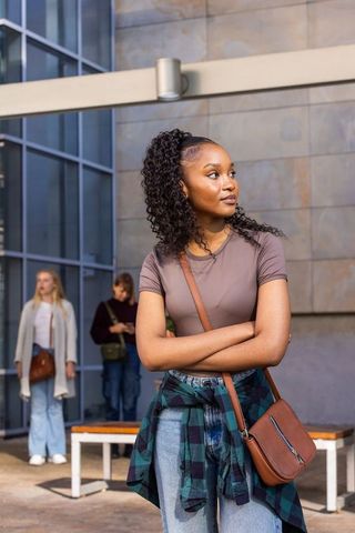 African american woman standing arms crossed in urban plaza wearing casual outfit