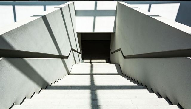 Minimalist Concrete Staircase Casting Dramatic Skylight Shadows and Geometric Lines