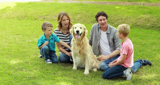 Family of four with two young boys bonding with their golden retriever in a grassy park. Suitable for themes of family time, pet companionship, and outdoor activities. Can be used for advertisements, family-focused content, or pet-care campaigns.
