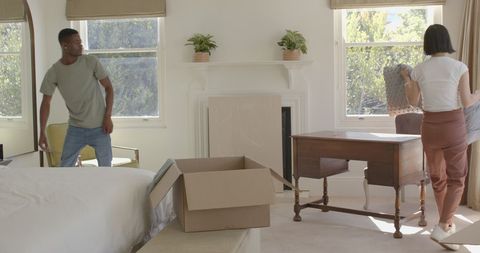 Couple unpacking moving boxes in sunlit living room