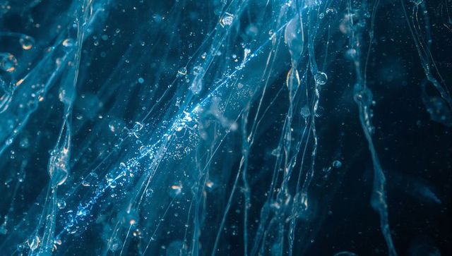 Cyan water strands glinting with suspended droplets and fine mist macro abstraction liquid