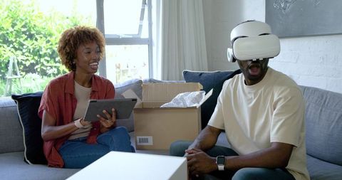 African American couple testing virtual reality headset with tablet and unpacked box