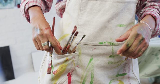 Abstract artist’s hands holding paintbrushes in apron pocket - Download Free Stock Images Pikwizard.com