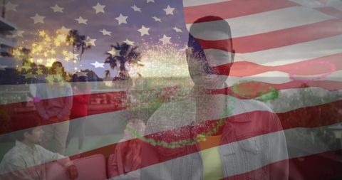 Standing man on waterfront terrace at dusk with us flag, fireworks and celebration overlay