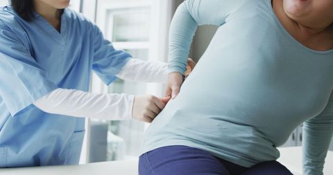 Female Physiotherapist Consulting Patient with Back Pain