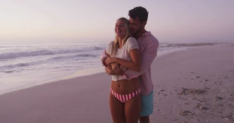 Embracing couple enjoying romantic beach sunset scenery