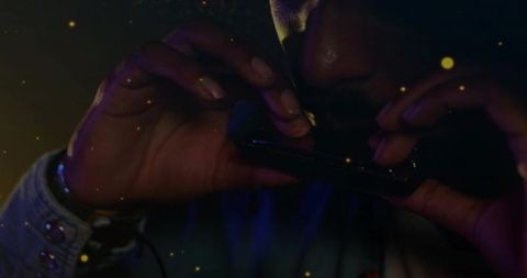 Indian musician playing harmonica closeup with moody blue and amber lighting and particles