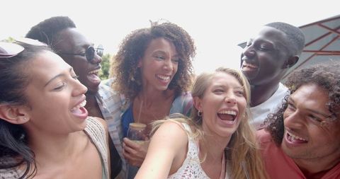 Diverse Young Friends Laughing Together Outdoors in Sunlight