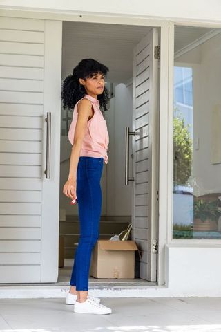 African american woman standing in modern foyer holding key fob unpacking moving boxes