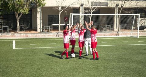 Soccer coach boosting team morale with high-fives during practice