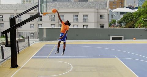 African American Male Athlete Practicing Basketball Dunk Outdoors