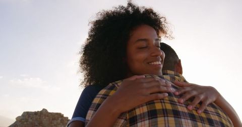 Young multiethnic couple embracing outdoors in sunlight