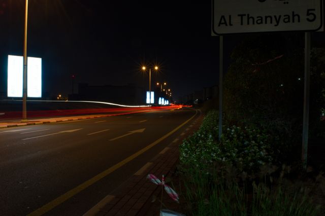 Long exposure capture of Al Thanyah road at night, highlighting dynamic light trails from moving cars. This can be used to convey a sense of motion and energy in urban night scenes. Ideal for use in marketing materials, travel blogs, and cityscape collections to illustrate nighttime urban atmosphere.