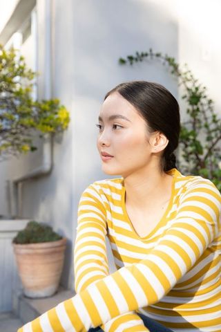 Contemplative Woman Sitting in Sunny Courtyard Near Succulent Plant