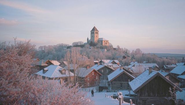 Serene Winter Dawn with Hikers in Snow-Covered Rural Village