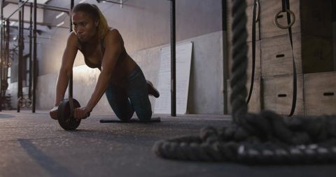 Focused Female Athlete Using Ab Wheel in Modern Gym