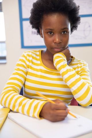 Focused african american girl writing at school desk