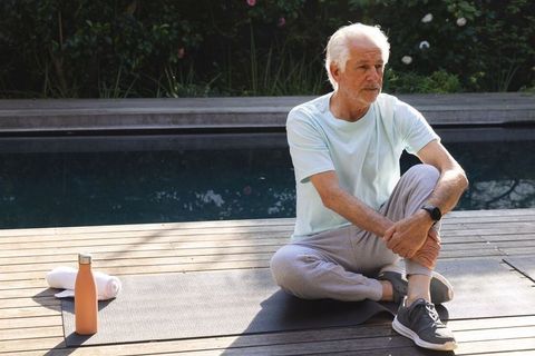 Senior man relaxing poolside practicing mindful meditation