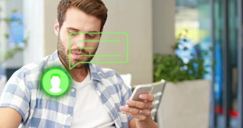 Young man checking smartphone with floating green chat icon in modern cafe