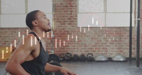Black Male Athlete Pausing and Breathing After Set in Industrial Gym with Kettlebells