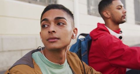Two Friends Relaxing Outdoors with Music and Backpacks