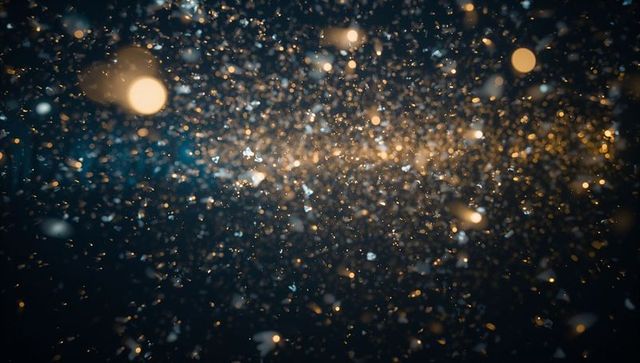 Shimmering gold and blue particle stream with bokeh orbs and light flares