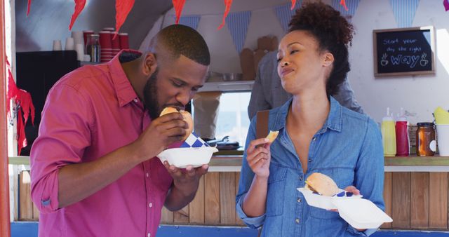 African american couple eating burgers and fries together at the food truck. food truck and street food concept