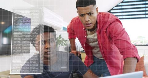 Two men analyzing code on laptop with binary data overlay for collaborative problem solving