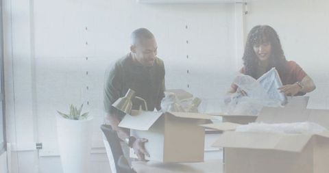 Team unpacking office supplies at conference table while organizing workspace and lighting