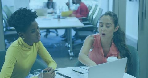 Women Reviewing Documents and Collaborating Over Laptop in Modern Office Meeting