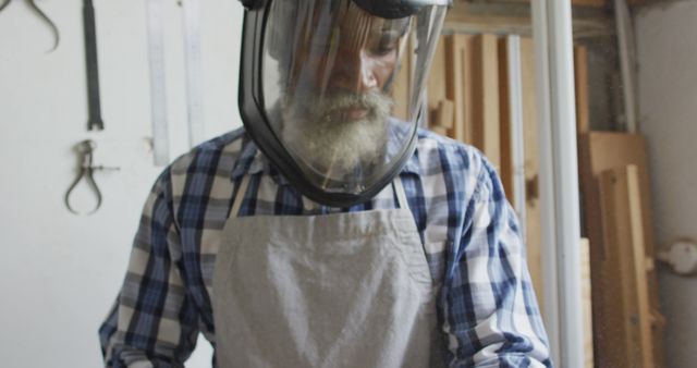African american male carpenter wearing protective helmet turning wood on a lathe at carpentry shop. Carpentry, craftsmanship and handwork concept